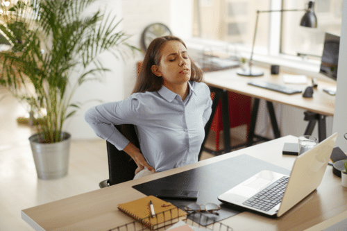 Woman sat at desk with back pain