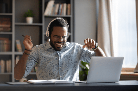 man sat at desk with headphones happy