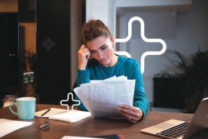 woman sat at table looking at papers worried