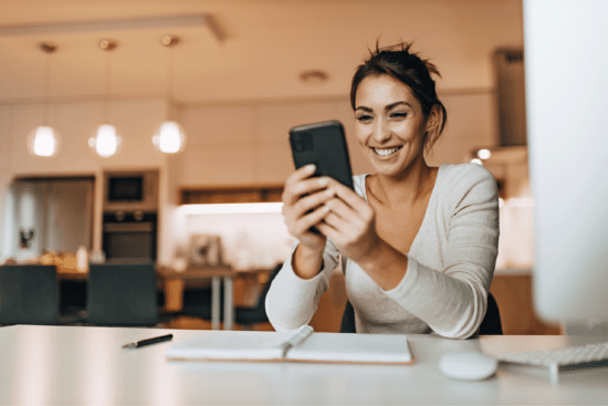 woman seated and smiling at phone