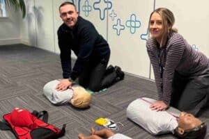 Male and female Medicash employees taking part in first aid training learning CPR