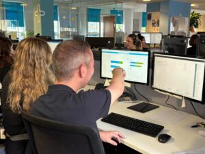 Male and female Medicash employees faced away looking at a computer screen
