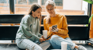 Adora two women chatting over phone with coffee